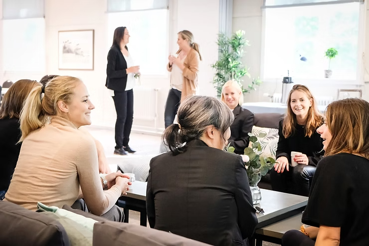 Grupp kvinnor som samtalar och skrattar i en ljus lounge under ett möte