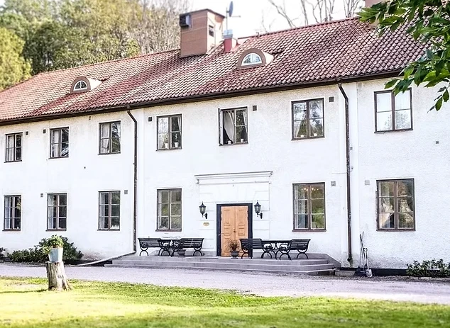 Philipssonska annexet på Ulvhälls Herrgård – vit putsad byggnad med röd tegelpanntak och träportik, omgiven av grönskande park
